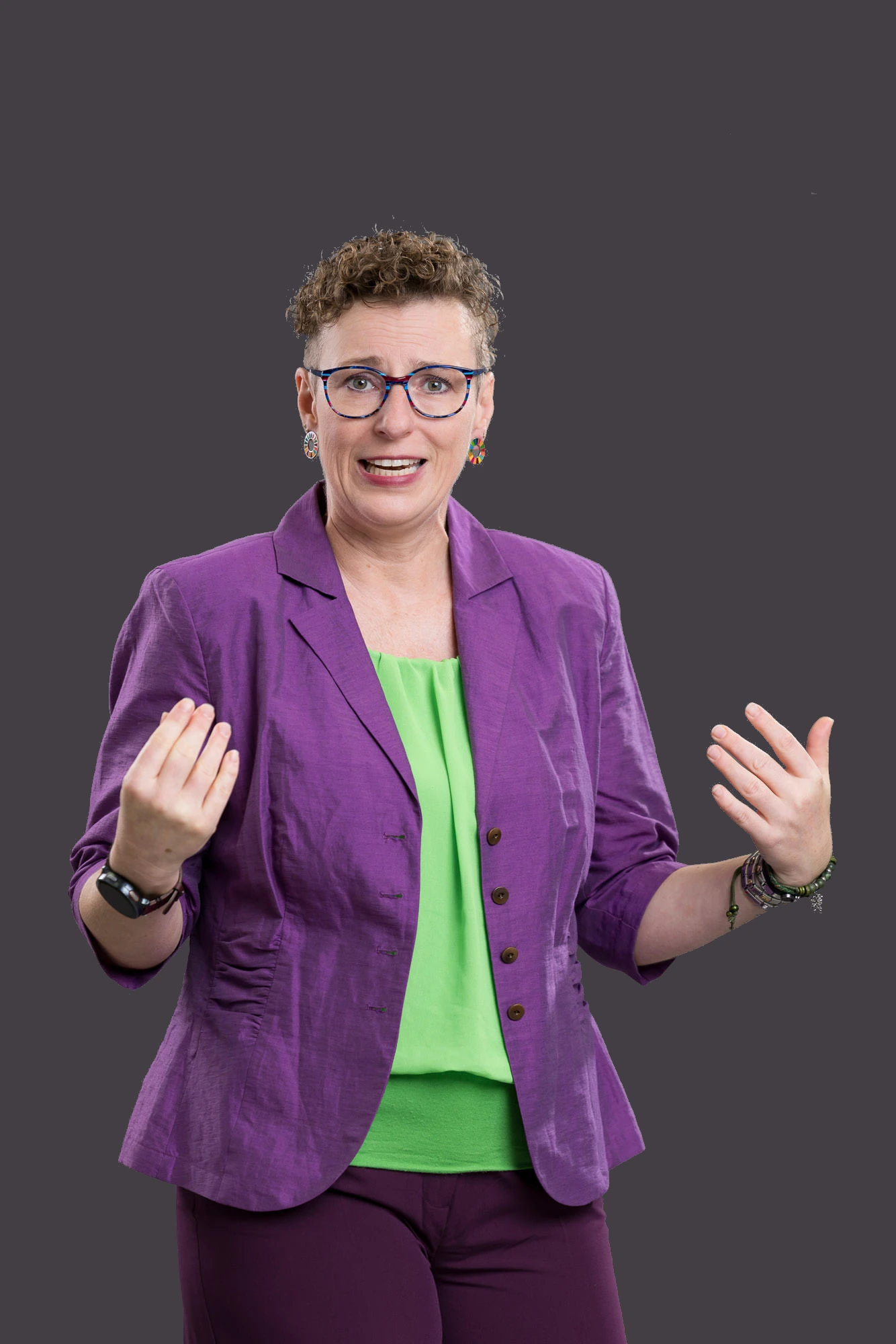 Nicole Schaufler sitzt in violettem Anzug verkehrt auf einem Holzsessel und spricht gerade